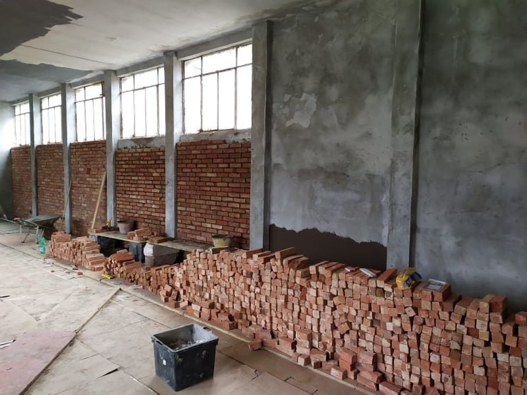 Industrial space with large windows and brick piles stacked along the concrete floor