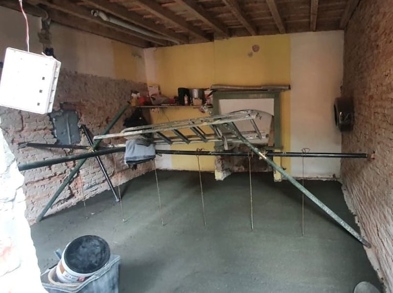 Unfinished basement room with wooden scaffold structures, concrete floor, yellow walls, and construction materials scattered throughout